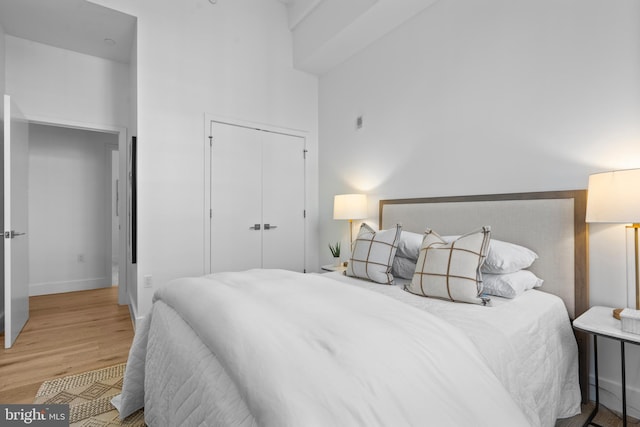 bedroom featuring a closet, baseboards, wood finished floors, and a towering ceiling