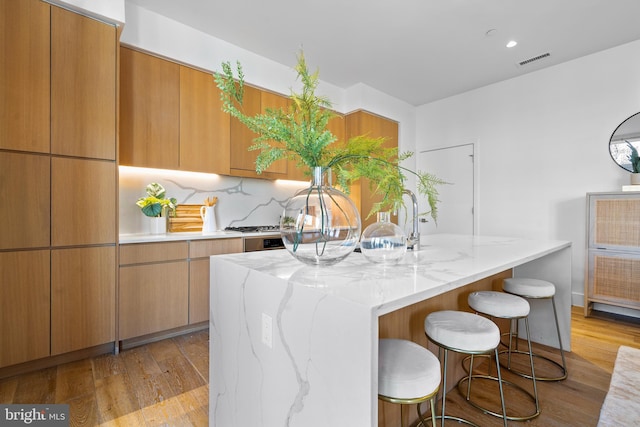 kitchen with light stone countertops, visible vents, and light wood-type flooring