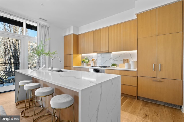 kitchen featuring backsplash, modern cabinets, light wood-type flooring, and a sink