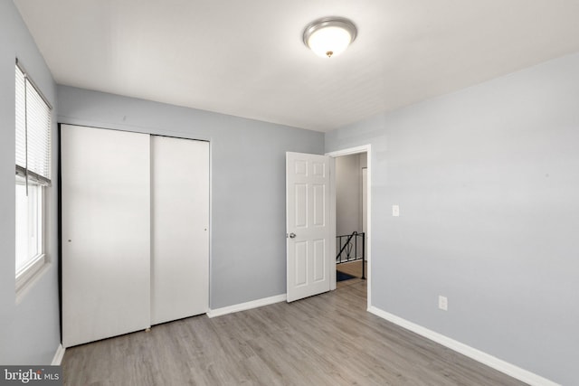 unfurnished bedroom featuring a closet, baseboards, and wood finished floors