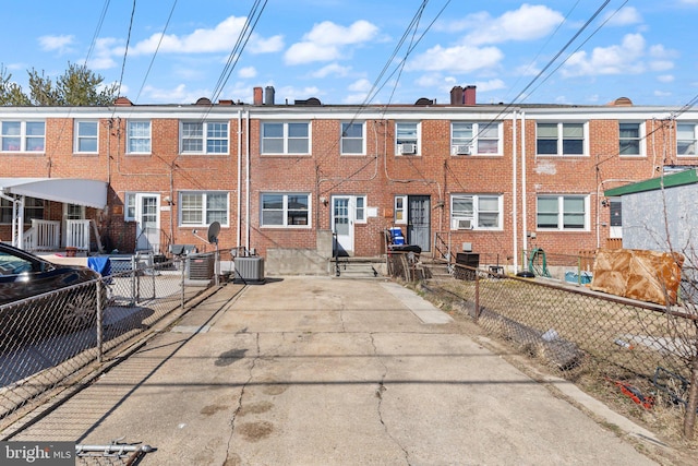 view of front of house featuring fence private yard, brick siding, entry steps, and central AC unit