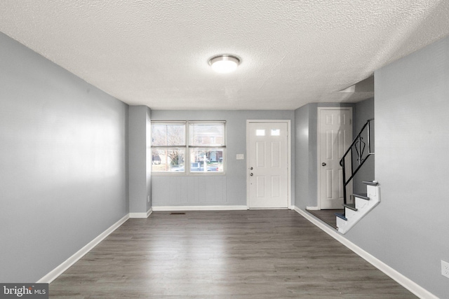 entrance foyer with stairs, baseboards, dark wood finished floors, and a textured ceiling