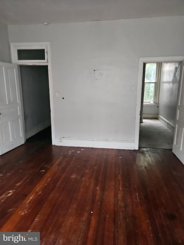 unfurnished room with dark wood-type flooring and baseboards