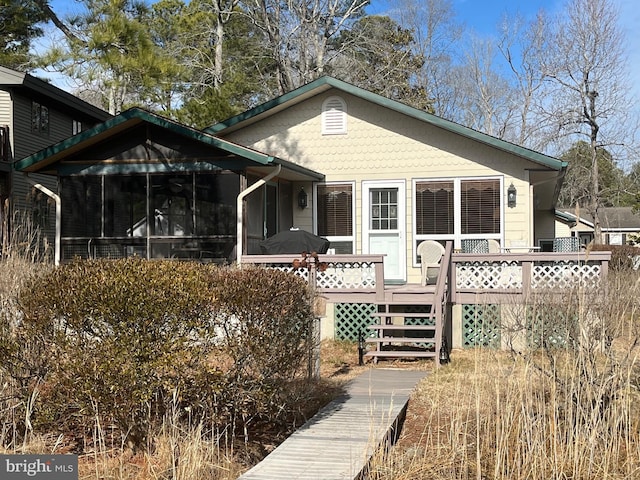 back of property with a wooden deck and a sunroom