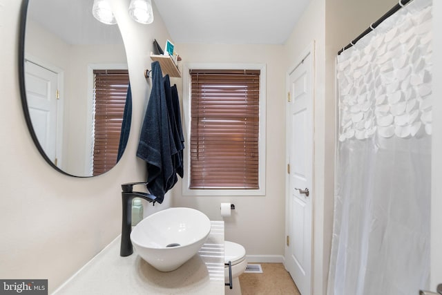 bathroom featuring toilet, a sink, visible vents, and baseboards