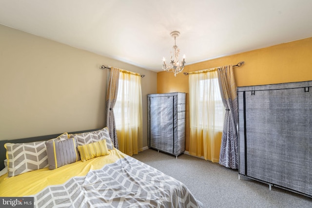 carpeted bedroom featuring multiple windows and an inviting chandelier