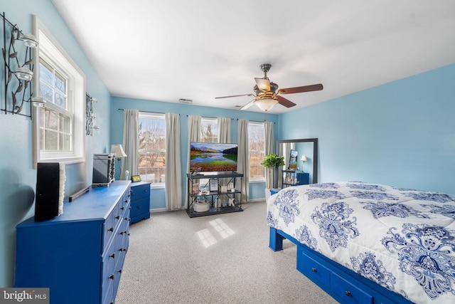 bedroom with a ceiling fan, light colored carpet, and visible vents