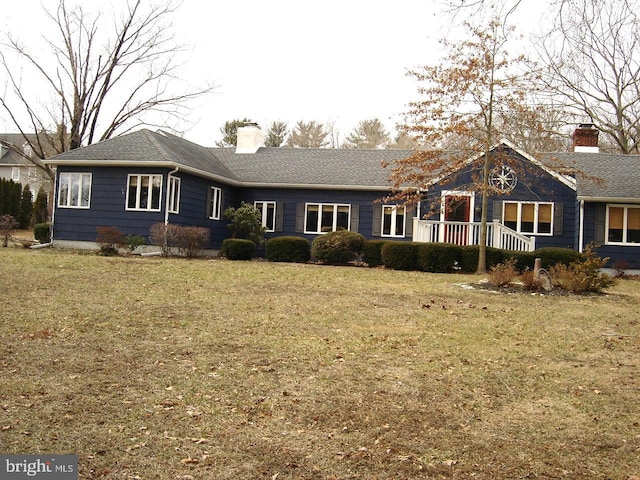 ranch-style home featuring roof with shingles, a chimney, and a front yard