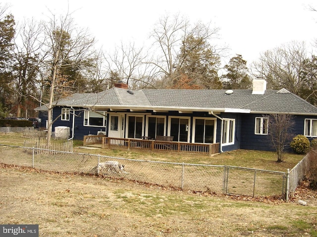 back of house with a fenced backyard, a chimney, roof with shingles, and a yard