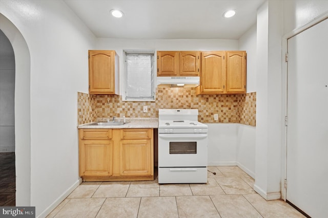 kitchen with arched walkways, light countertops, under cabinet range hood, white stove, and a sink