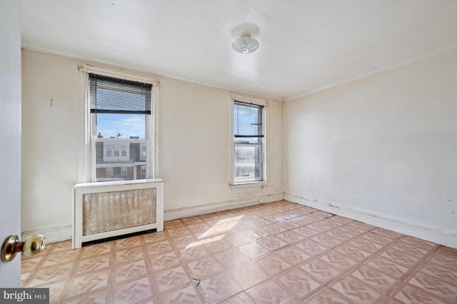 empty room featuring a wealth of natural light, crown molding, and baseboards