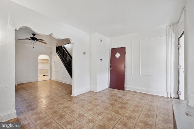 foyer entrance with arched walkways, ceiling fan, and stairs