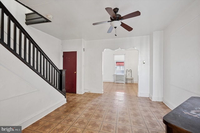 entryway with a ceiling fan, arched walkways, baseboards, and stairs