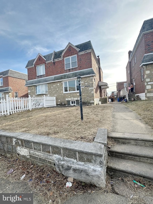 view of front facade featuring brick siding and fence