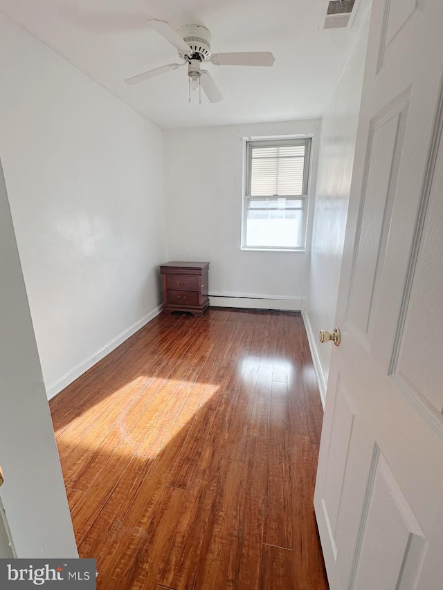 unfurnished room with baseboards, visible vents, a ceiling fan, dark wood finished floors, and baseboard heating