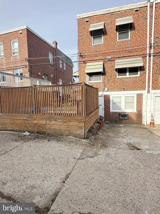 back of house with brick siding and a wooden deck