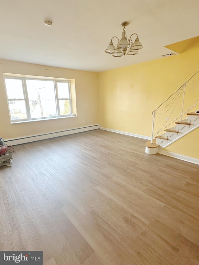 unfurnished living room with a notable chandelier, stairway, a baseboard heating unit, wood finished floors, and baseboards