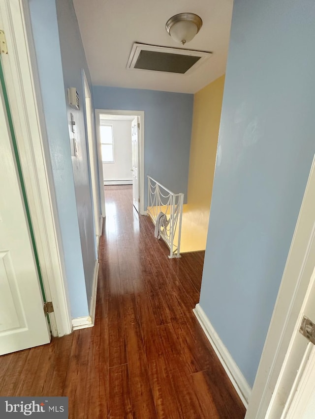 corridor featuring dark wood-style floors, a baseboard radiator, and baseboards