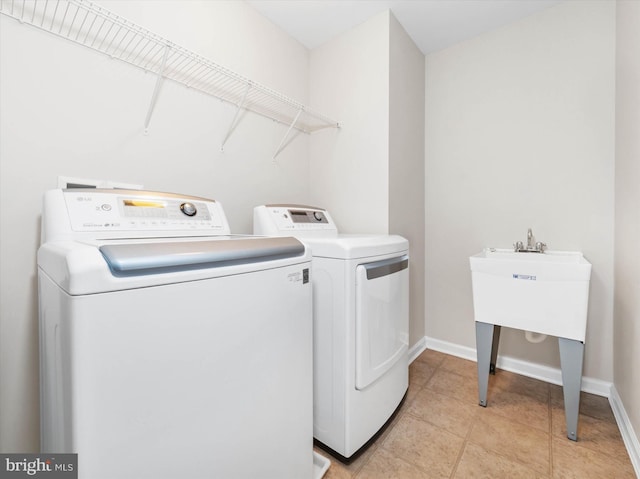 washroom featuring laundry area, light tile patterned flooring, washing machine and dryer, and baseboards