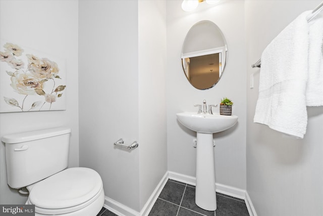 half bathroom with tile patterned flooring, toilet, and baseboards