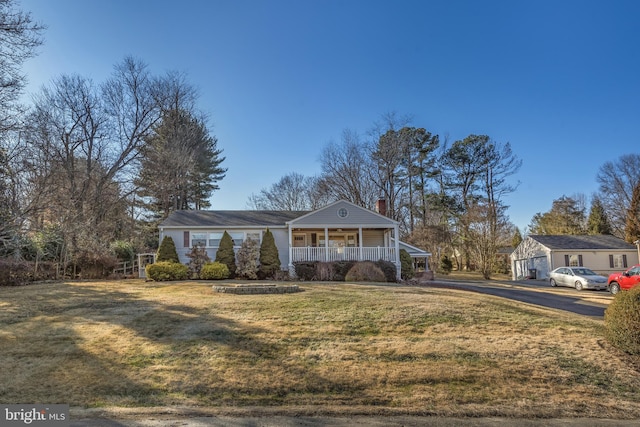 view of front of home featuring covered porch, a chimney, and a front yard