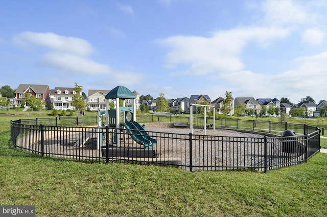 community jungle gym featuring a residential view, a yard, and fence