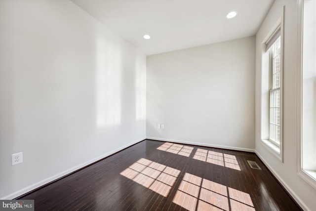 unfurnished room featuring dark wood-style floors, visible vents, and baseboards