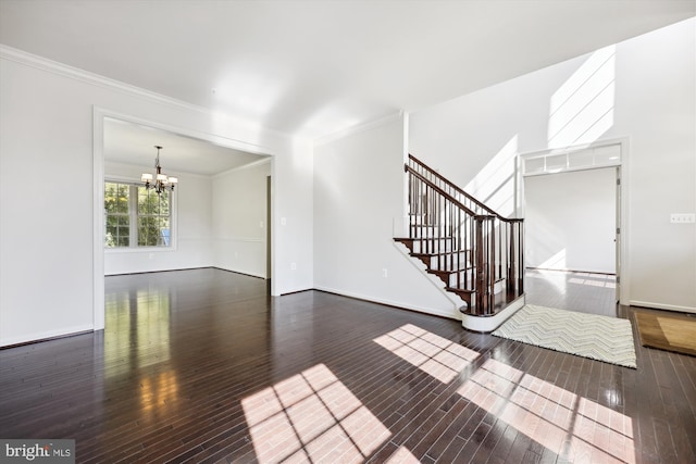 unfurnished living room with wood-type flooring, crown molding, stairway, and a notable chandelier