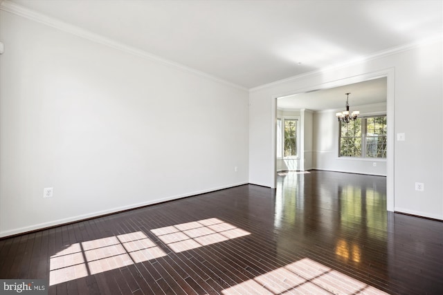 empty room with an inviting chandelier, crown molding, baseboards, and hardwood / wood-style floors