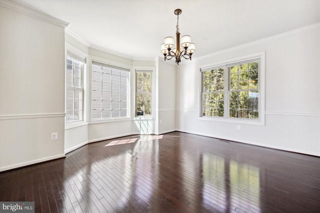 empty room with wood-type flooring, a notable chandelier, crown molding, and baseboards