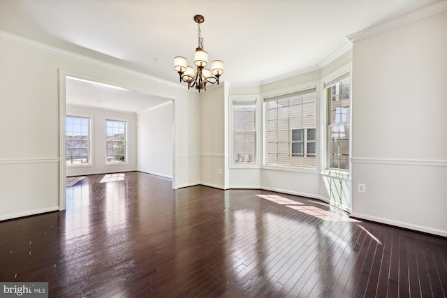 spare room with a chandelier, wood-type flooring, baseboards, and crown molding