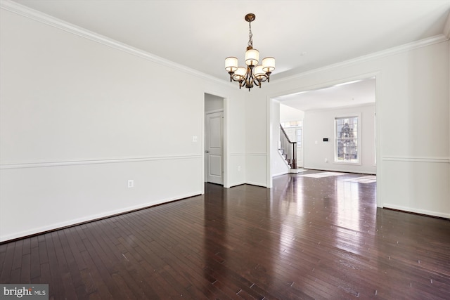 spare room with ornamental molding, a chandelier, hardwood / wood-style floors, and stairs