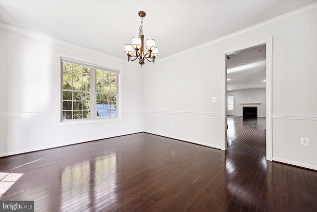 unfurnished room featuring baseboards, hardwood / wood-style floors, crown molding, a fireplace, and a notable chandelier