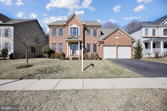 colonial home featuring a garage, a front yard, aphalt driveway, and brick siding