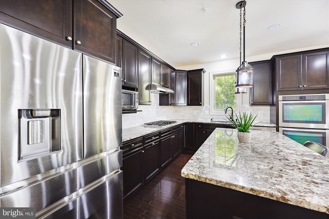 kitchen featuring dark brown cabinetry, light stone countertops, appliances with stainless steel finishes, and decorative backsplash