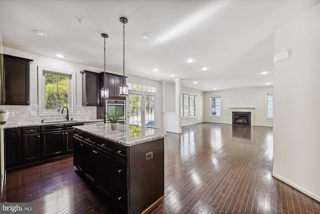 kitchen with dark wood-type flooring, backsplash, a sink, and oven