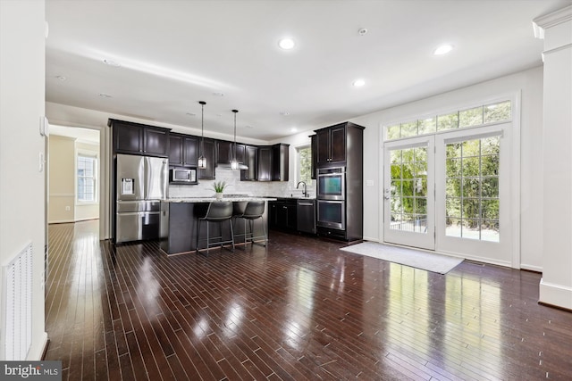 kitchen featuring tasteful backsplash, appliances with stainless steel finishes, dark brown cabinets, and dark wood-type flooring