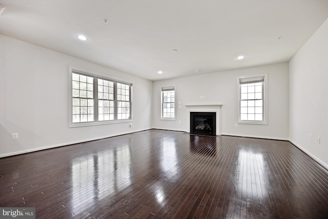 unfurnished living room with a fireplace with flush hearth, baseboards, wood finished floors, and recessed lighting