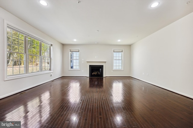 unfurnished living room with recessed lighting, a fireplace with flush hearth, visible vents, baseboards, and wood-type flooring