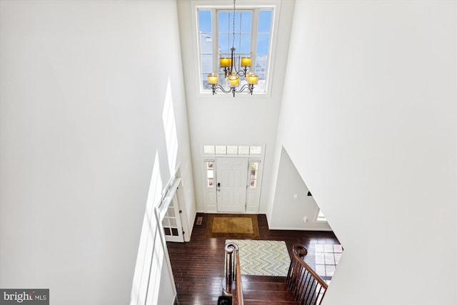 foyer entrance with baseboards, dark wood finished floors, a towering ceiling, an inviting chandelier, and stairs