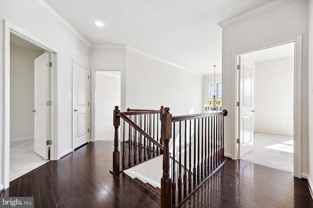 hall with ornamental molding, wood-type flooring, visible vents, and an upstairs landing