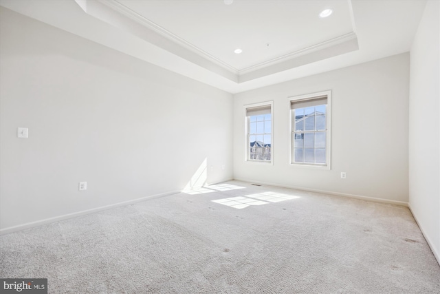 carpeted empty room featuring a tray ceiling, crown molding, baseboards, and recessed lighting