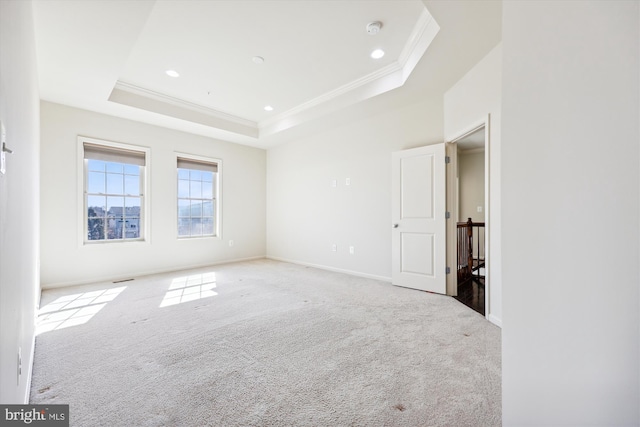 carpeted empty room featuring ornamental molding, a raised ceiling, and recessed lighting