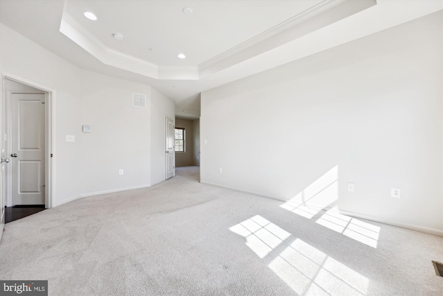 unfurnished bedroom featuring light carpet, a tray ceiling, and ornamental molding