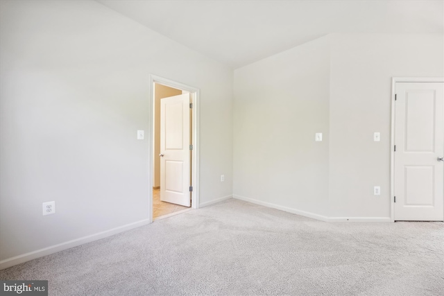 spare room featuring baseboards and light colored carpet