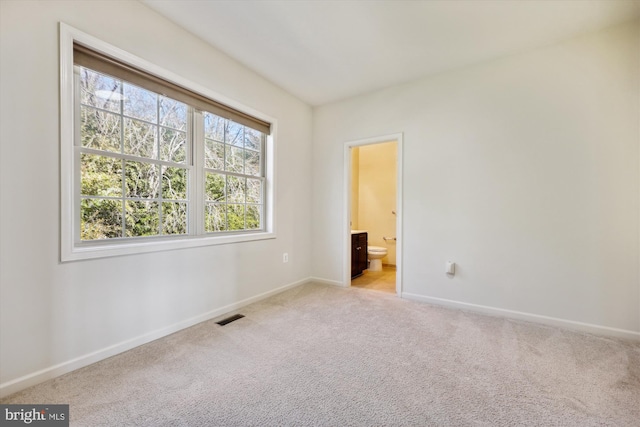 unfurnished bedroom featuring baseboards, visible vents, ensuite bath, and carpet flooring