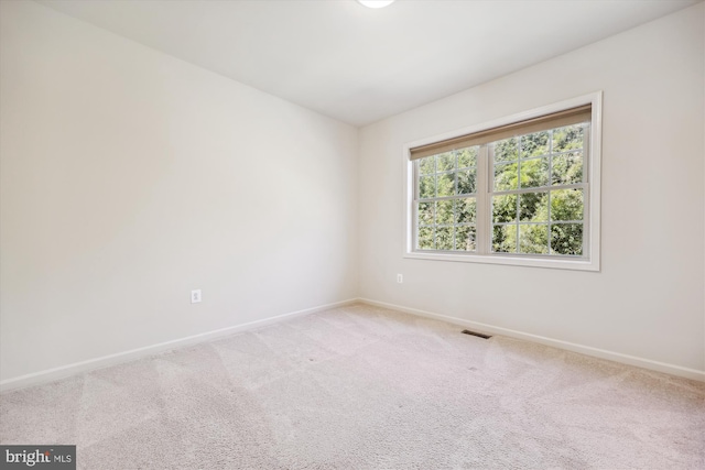 unfurnished room with carpet floors, visible vents, and baseboards