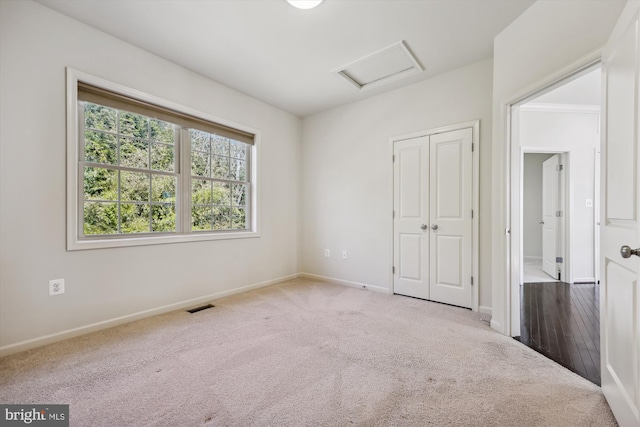 unfurnished bedroom with attic access, visible vents, baseboards, carpet, and a closet