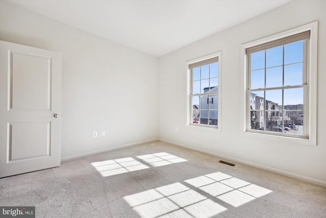 carpeted spare room with plenty of natural light, visible vents, and baseboards