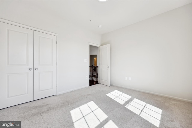 unfurnished bedroom with carpet floors, a closet, and baseboards